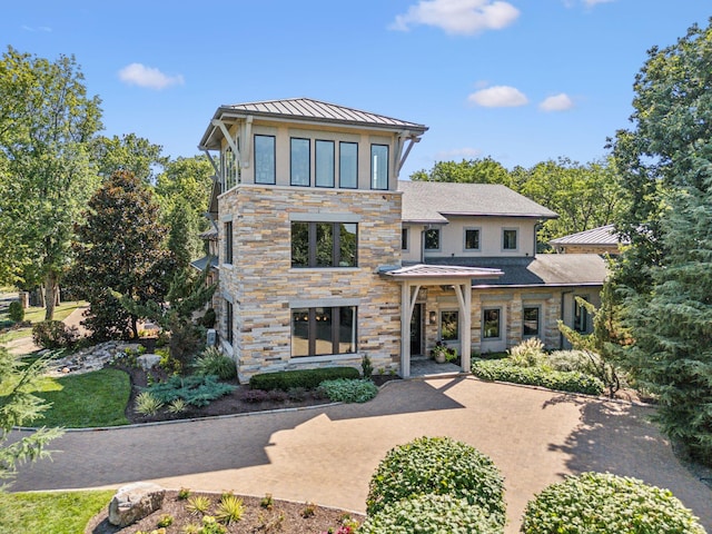 contemporary house featuring stone siding, a standing seam roof, and metal roof