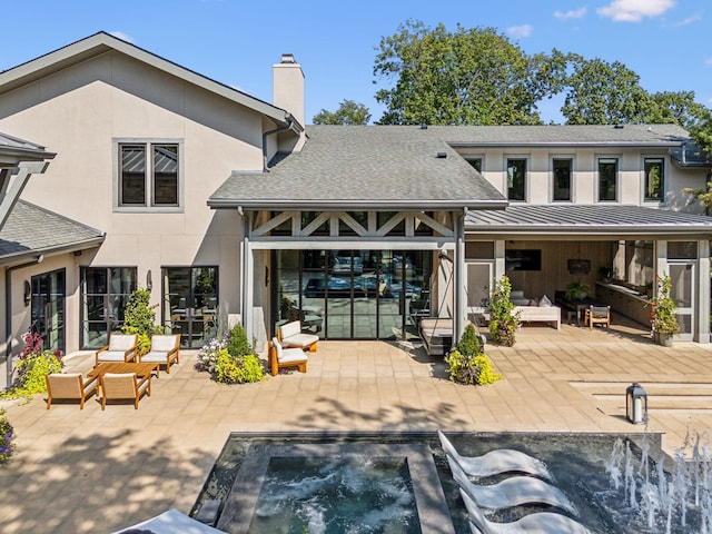 back of property featuring stucco siding, a standing seam roof, a patio area, metal roof, and an in ground hot tub