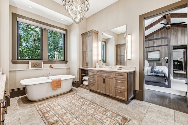 bathroom featuring ensuite bathroom, ceiling fan with notable chandelier, vanity, a freestanding bath, and vaulted ceiling