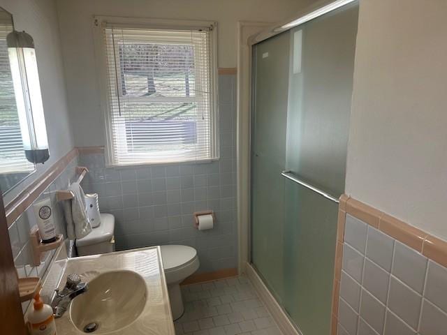 bathroom with toilet, a stall shower, tile walls, and tile patterned floors