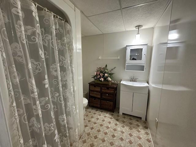 full bath with a drop ceiling, a shower with shower curtain, toilet, tile patterned floors, and vanity