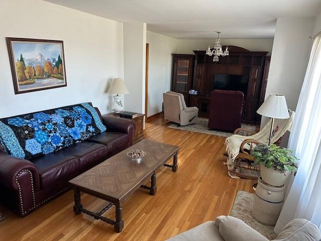 living area with wood finished floors and an inviting chandelier