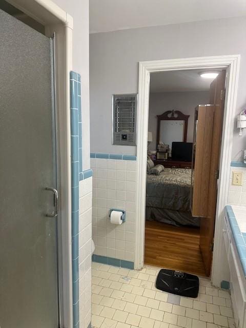 ensuite bathroom with ensuite bath, tile patterned flooring, tile walls, and a shower stall