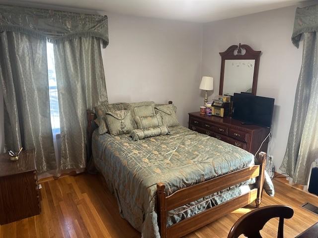 bedroom with multiple windows, visible vents, and wood finished floors