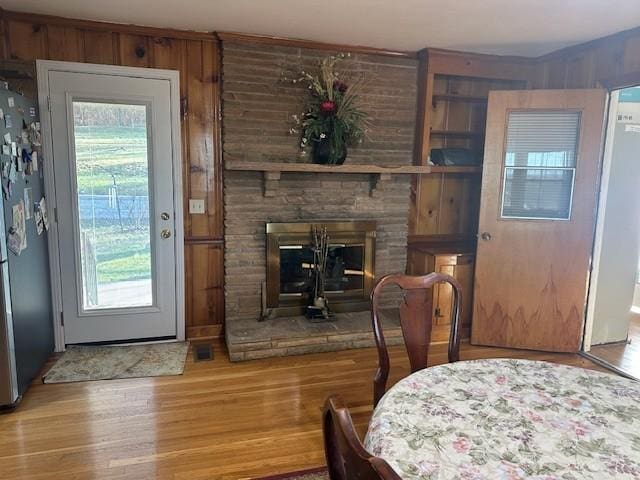 dining room with a fireplace, wood finished floors, and wooden walls