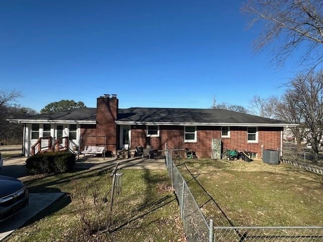 back of property featuring brick siding, a chimney, a lawn, fence private yard, and cooling unit