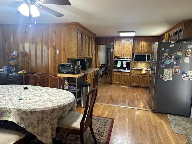 kitchen with decorative backsplash, brown cabinetry, appliances with stainless steel finishes, light countertops, and light wood-style floors