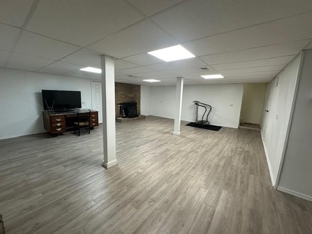 finished basement featuring a paneled ceiling and wood finished floors