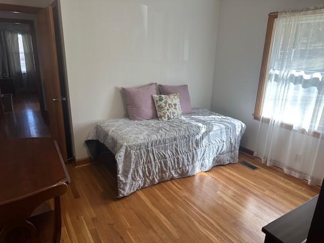 bedroom with multiple windows, wood finished floors, and visible vents