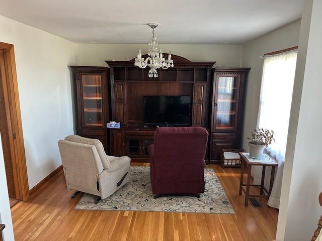 living room featuring an inviting chandelier, baseboards, and wood finished floors