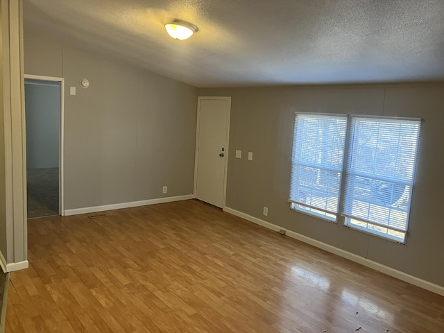 unfurnished room featuring a textured ceiling, light wood finished floors, and baseboards