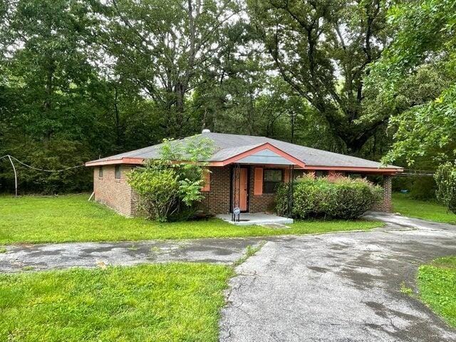 view of front of house featuring a front yard, brick siding, and driveway