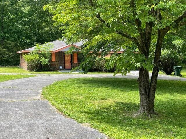 ranch-style house with brick siding, driveway, and a front lawn