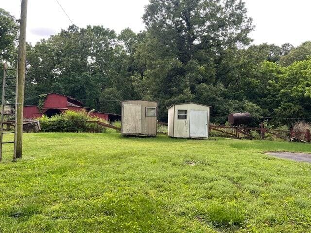 view of yard with an outdoor structure, a storage unit, and fence