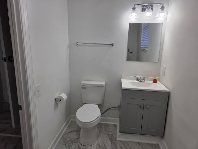 half bath with marble finish floor, toilet, vanity, and baseboards