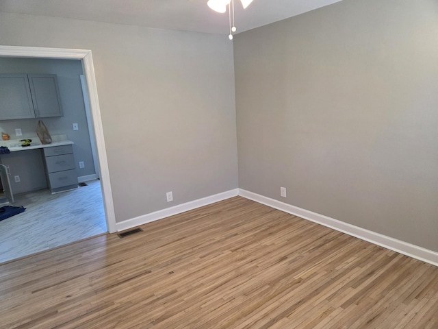 unfurnished room featuring light wood finished floors, visible vents, and baseboards