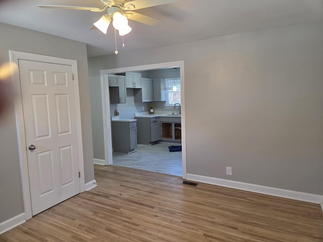 interior space with light wood finished floors, a sink, visible vents, and baseboards