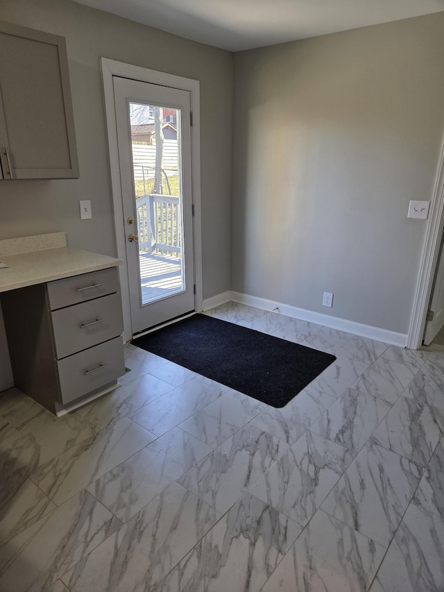 doorway with marble finish floor and baseboards