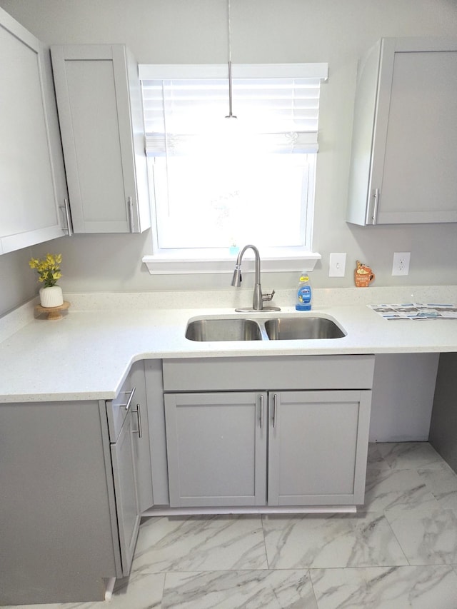 kitchen with marble finish floor, gray cabinets, a sink, and light countertops