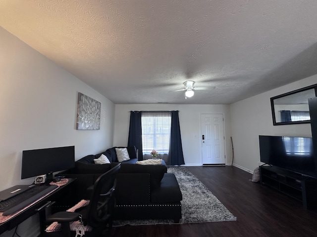 living room with a ceiling fan, a textured ceiling, baseboards, and wood finished floors