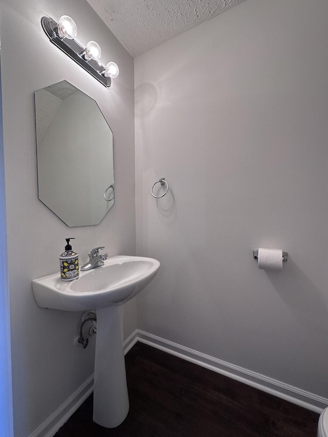 bathroom featuring a textured ceiling, baseboards, and wood finished floors