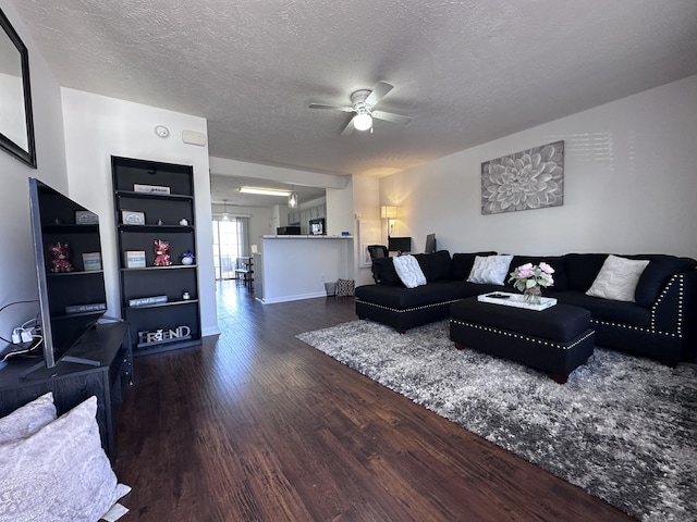 living room featuring ceiling fan, a textured ceiling, wood finished floors, and baseboards