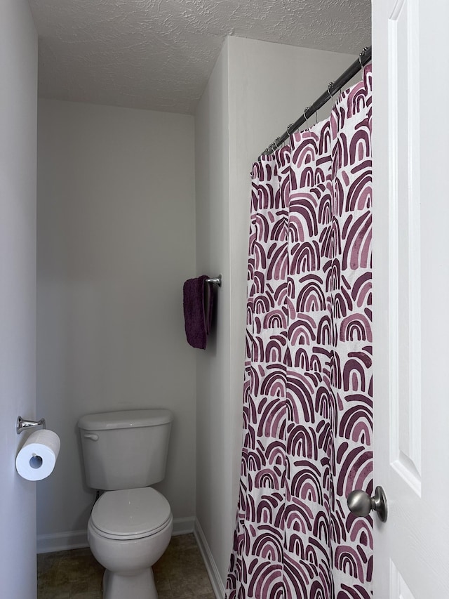 bathroom featuring tile patterned flooring, baseboards, a textured ceiling, and toilet