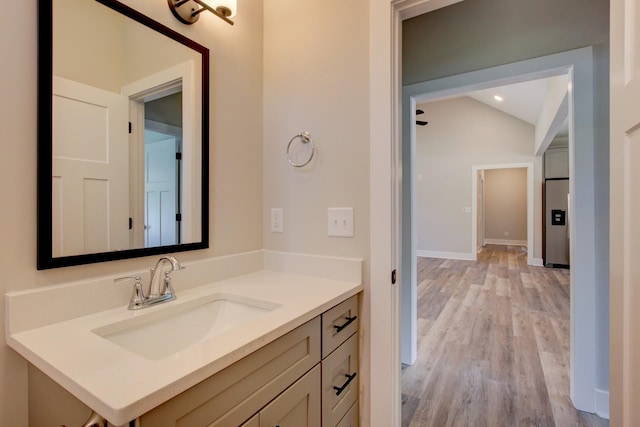 bathroom featuring lofted ceiling, wood finished floors, vanity, and baseboards