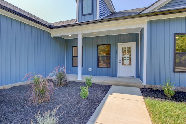 view of exterior entry with covered porch and board and batten siding