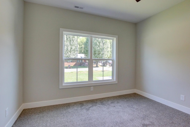 unfurnished room with carpet flooring, visible vents, and baseboards