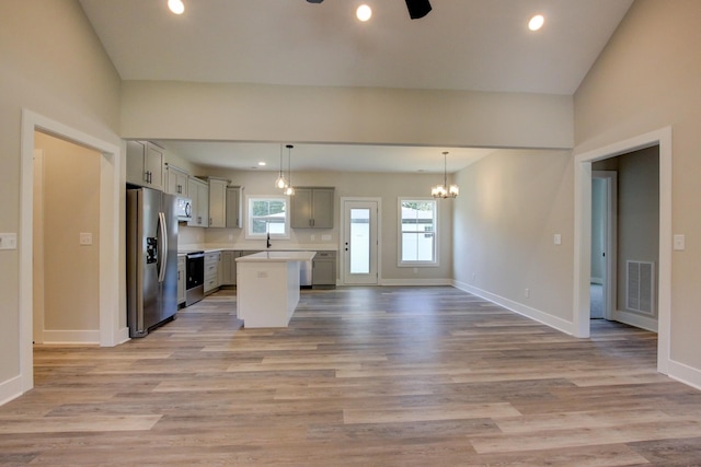 kitchen featuring stainless steel fridge, visible vents, light wood-style flooring, stove, and light countertops