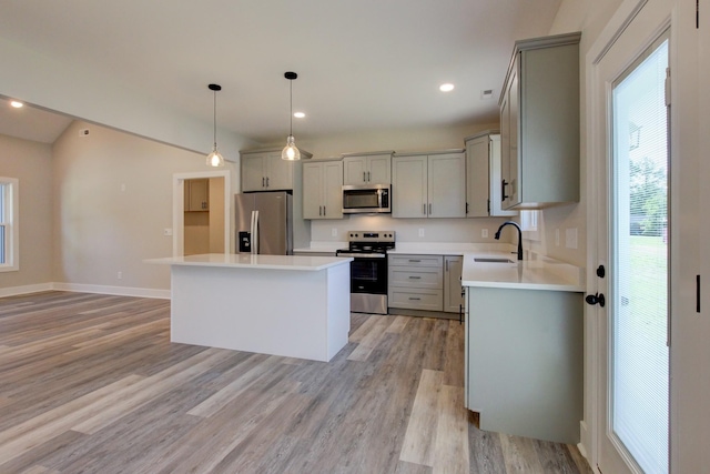 kitchen with stainless steel appliances, a kitchen island, a sink, and gray cabinetry