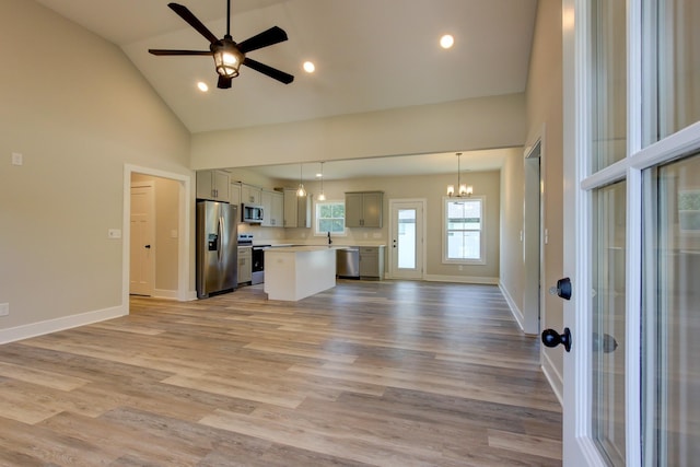 unfurnished living room featuring light wood-type flooring, recessed lighting, baseboards, and ceiling fan with notable chandelier