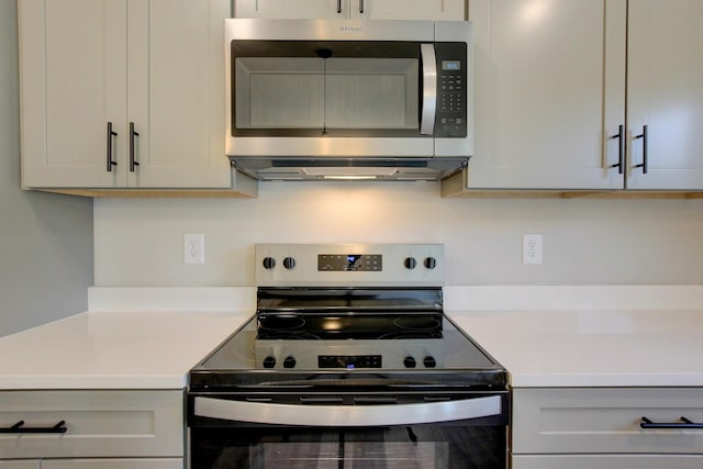 kitchen with light countertops, black range with electric cooktop, and stainless steel microwave