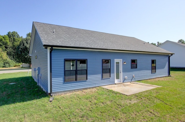 rear view of house featuring a shingled roof, a patio area, and a yard