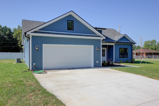 view of front of home featuring an attached garage, central air condition unit, fence, roof with shingles, and a front yard