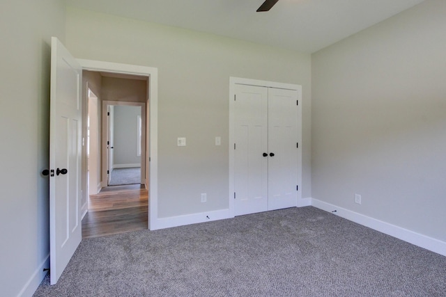 unfurnished bedroom featuring a ceiling fan, baseboards, dark carpet, and a closet