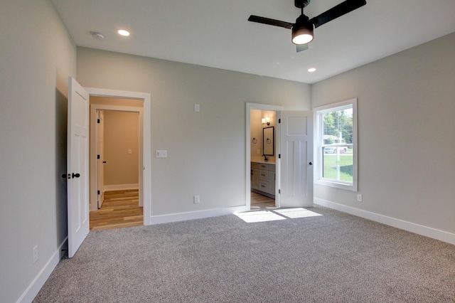 unfurnished bedroom with recessed lighting, baseboards, ensuite bathroom, and light colored carpet