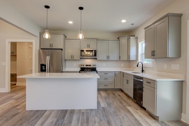 kitchen featuring stainless steel appliances, gray cabinets, a sink, and light wood-style flooring