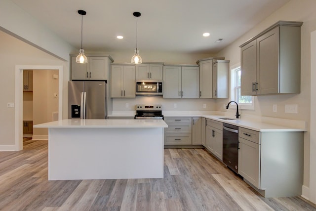 kitchen featuring appliances with stainless steel finishes, a sink, light wood finished floors, and gray cabinetry