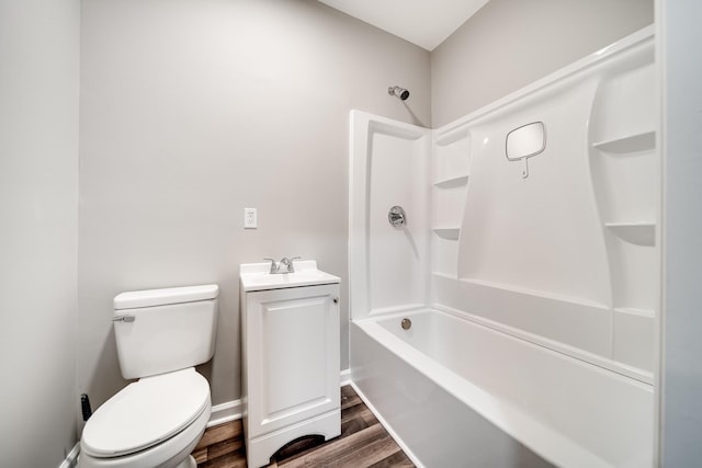 bathroom featuring baseboards, toilet, wood finished floors, shower / washtub combination, and a sink