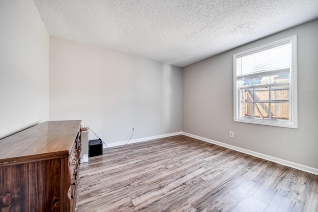 spare room featuring a textured ceiling, baseboards, and wood finished floors