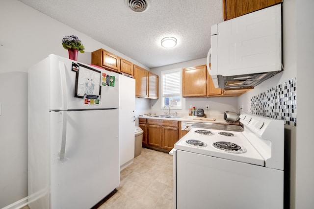 kitchen with white appliances, visible vents, brown cabinetry, light countertops, and a sink