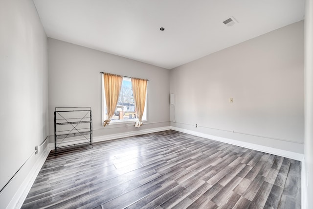 spare room with baseboards and wood finished floors