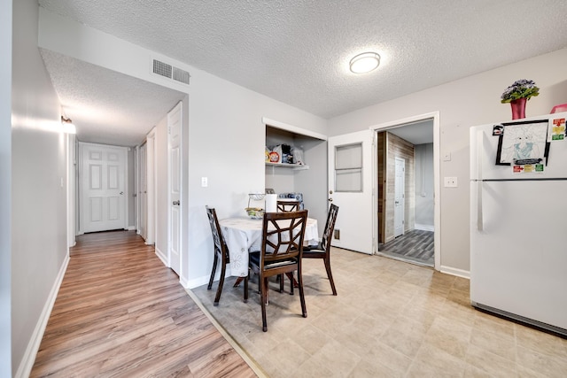 dining room featuring visible vents, a textured ceiling, and baseboards