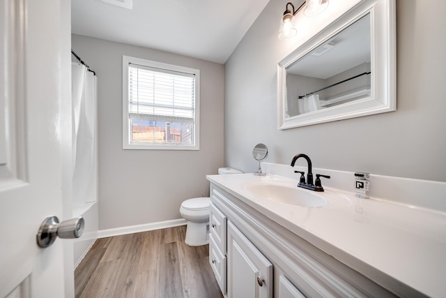 bathroom featuring baseboards, toilet, a shower with curtain, wood finished floors, and vanity