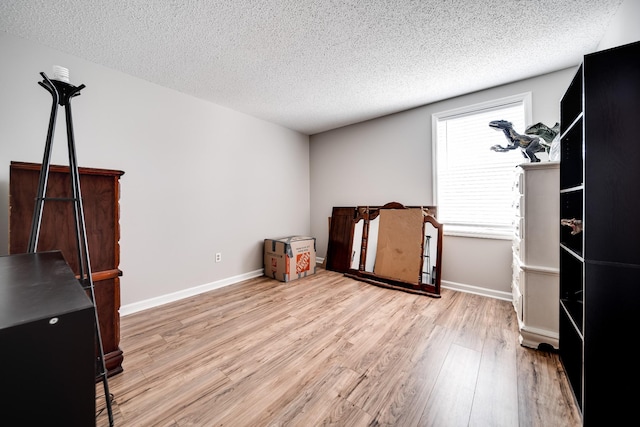 bedroom with a textured ceiling, baseboards, and wood finished floors