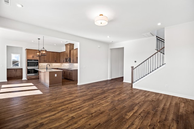 kitchen with appliances with stainless steel finishes, open floor plan, a sink, and an island with sink