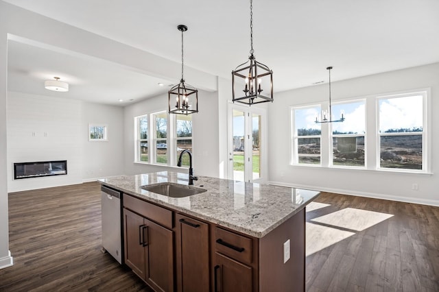 kitchen featuring dark wood-style floors, stainless steel dishwasher, open floor plan, a large fireplace, and a sink