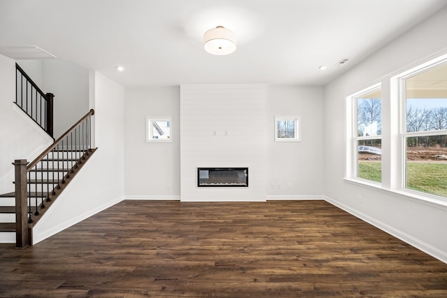 unfurnished living room with a fireplace, baseboards, and dark wood-type flooring